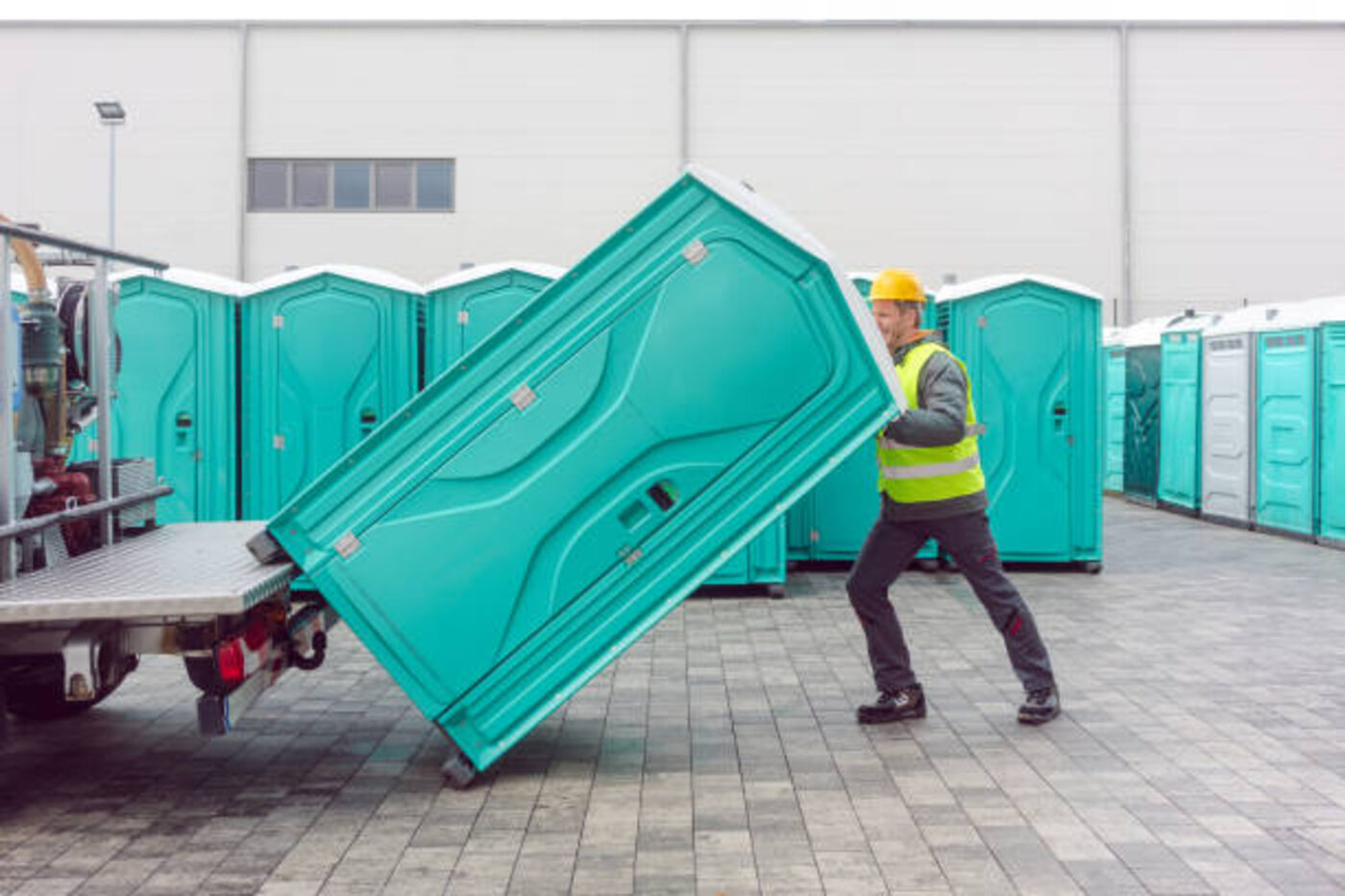 Septic pumping truck servicing a portable toilet on site